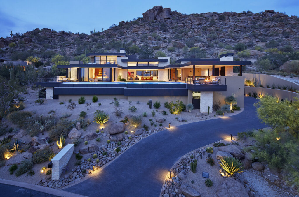 A photo of a warm modern home in the desert at dusk, designed by architecture firm Charles R. Stinson Architecture and Design